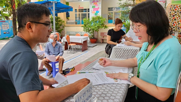 Phụ huynh đến nộp hồ sơ nhập học cho con vào lớp 1 Trường tiểu học Trần Bình Trọng, Q.5, TP.HCM sáng 13-6 - Ảnh: NHƯ HÙNG